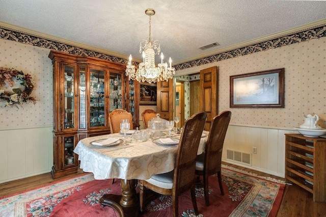 dining room with dark hardwood / wood-style flooring, ornamental molding, a textured ceiling, and an inviting chandelier