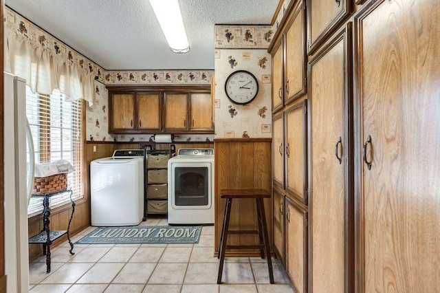 laundry room with light tile patterned flooring, cabinets, a textured ceiling, and washing machine and clothes dryer