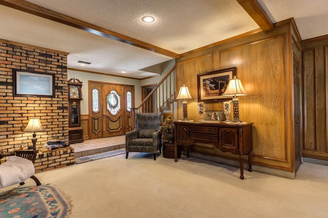 sitting room featuring beamed ceiling, light colored carpet, ornamental molding, and a textured ceiling