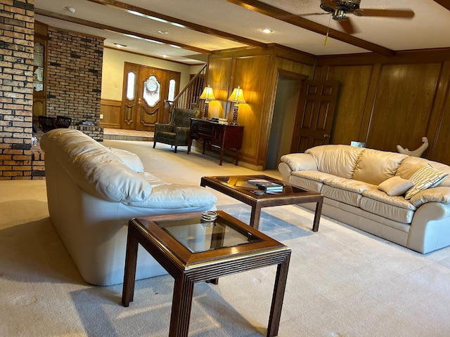 carpeted living room featuring ceiling fan, a brick fireplace, wooden walls, and beam ceiling