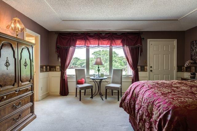 bedroom with light colored carpet and a textured ceiling