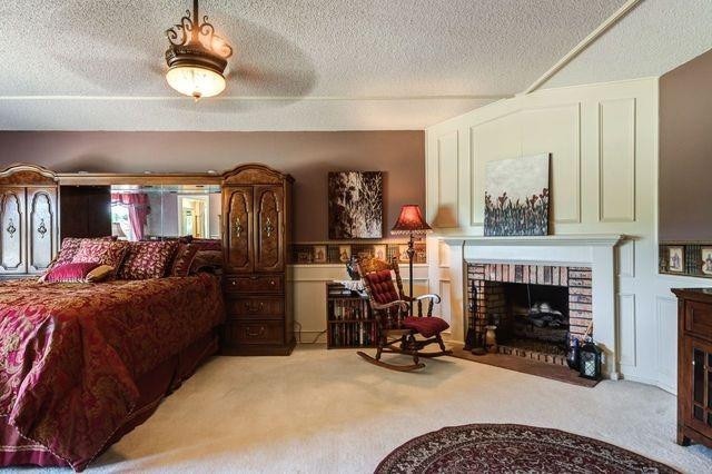 bedroom with light carpet, a fireplace, and a textured ceiling