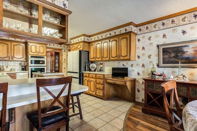 kitchen featuring a kitchen bar, a textured ceiling, fridge, white dishwasher, and double oven