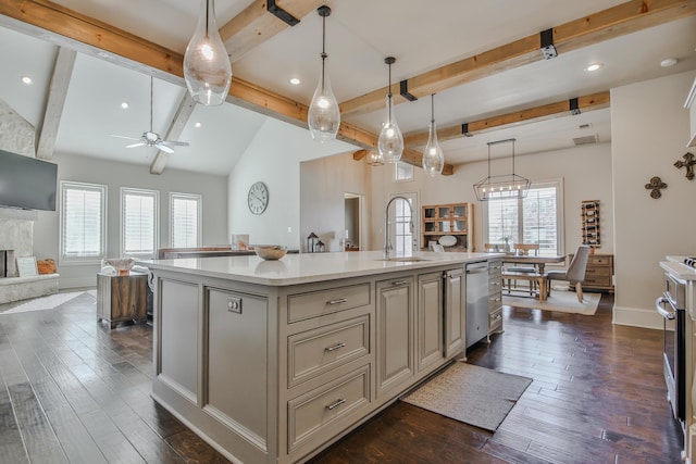 kitchen featuring a kitchen island with sink, sink, decorative light fixtures, and a fireplace