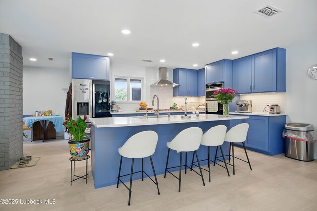 4509 76th St, Lubbock, TX 79424 - kitchen featuring wall chimney range hood, blue cabinets, tasteful backsplash, light countertops, and recessed lighting