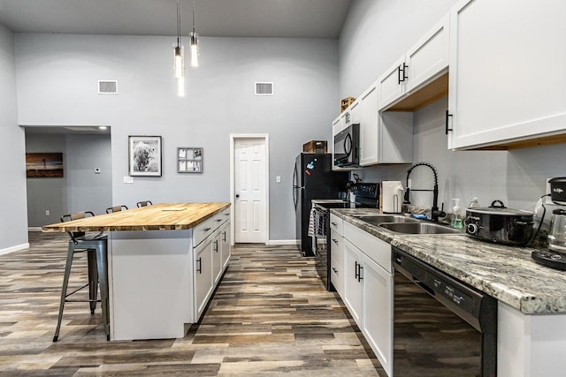 kitchen featuring white cabinetry, decorative light fixtures, black appliances, and a center island