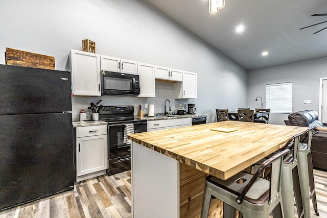 kitchen featuring white cabinetry, a kitchen breakfast bar, a kitchen island, and black appliances