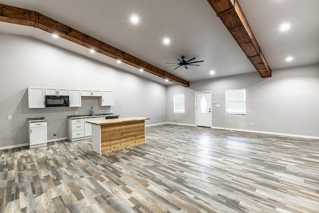 kitchen featuring sink, ceiling fan, light hardwood / wood-style floors, white cabinets, and beamed ceiling