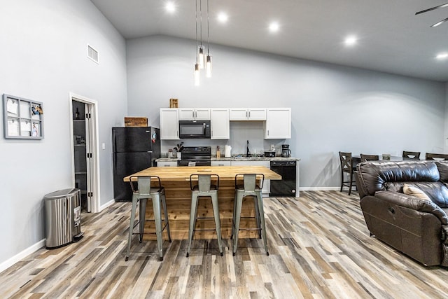 kitchen featuring a kitchen island, butcher block countertops, decorative light fixtures, white cabinets, and black appliances