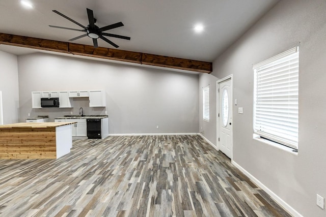 kitchen featuring hardwood / wood-style flooring, white cabinets, beam ceiling, and black appliances