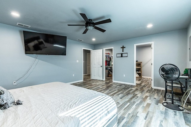 bedroom with ceiling fan, wood-type flooring, a spacious closet, and a closet