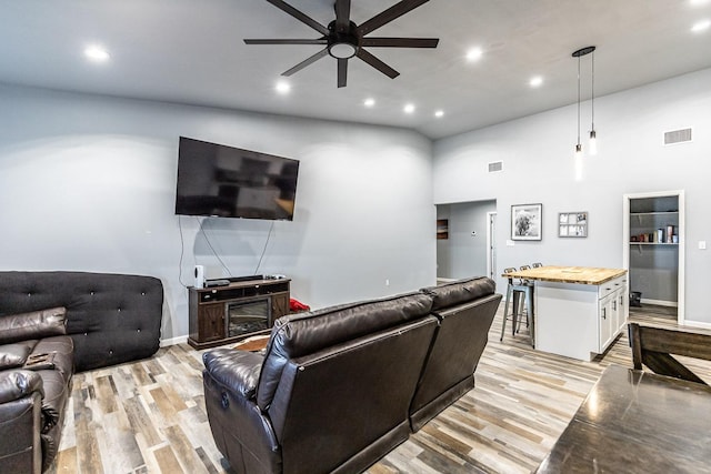 living room featuring a towering ceiling, ceiling fan, and light hardwood / wood-style flooring