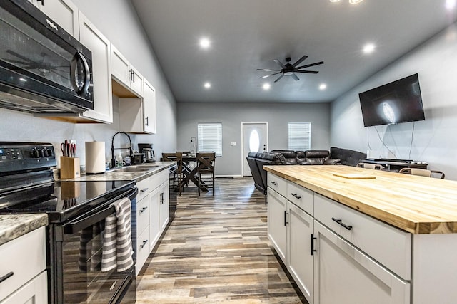 kitchen with wood counters, sink, white cabinets, black appliances, and light hardwood / wood-style flooring