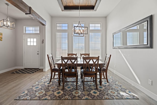 dining space featuring baseboards, wood finished floors, and an inviting chandelier