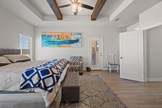 bedroom with wood finished floors, beamed ceiling, baseboards, visible vents, and a ceiling fan