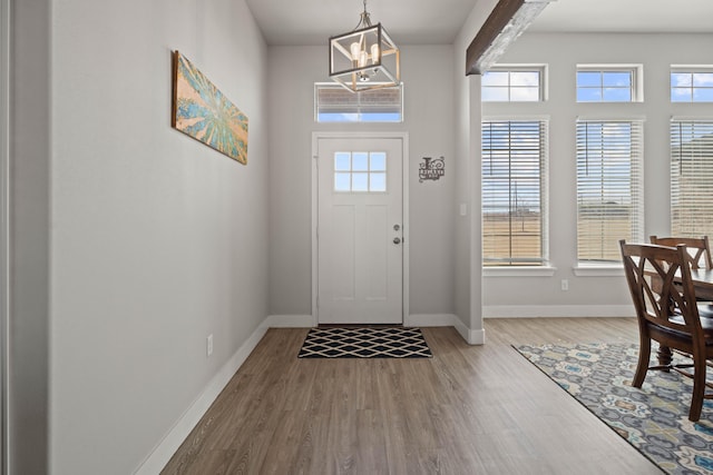 foyer with a notable chandelier, wood finished floors, and baseboards