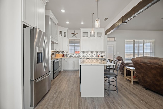 kitchen featuring stainless steel appliances, a kitchen breakfast bar, light wood-type flooring, visible vents, and open floor plan
