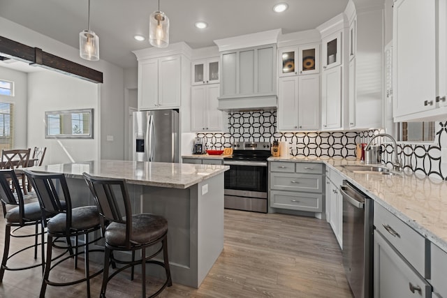 kitchen with decorative backsplash, a sink, appliances with stainless steel finishes, a center island, and a kitchen bar