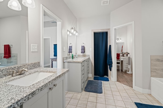 bathroom featuring tile patterned floors, visible vents, a bathtub, and a sink
