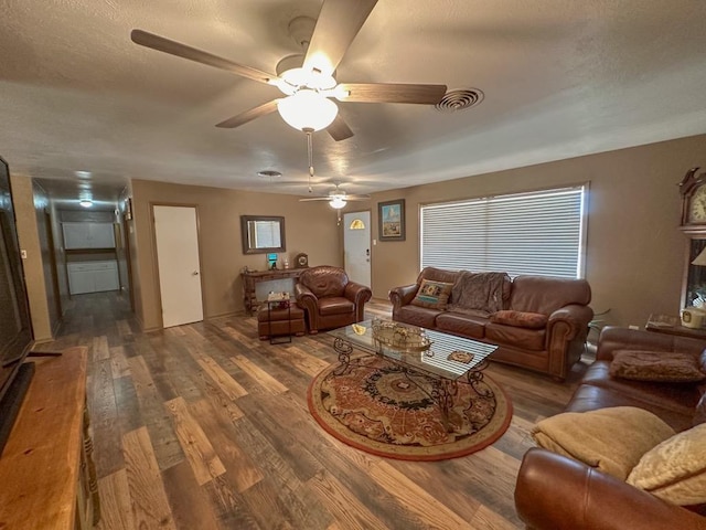 living area featuring a textured ceiling, wood finished floors, and visible vents