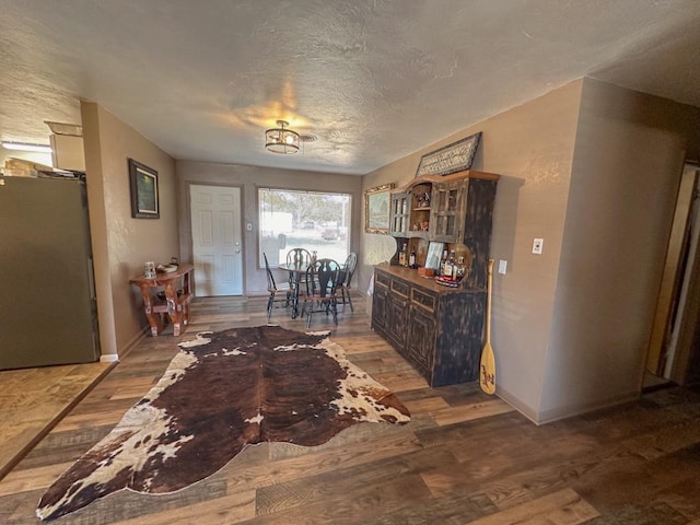 unfurnished dining area featuring a textured ceiling, baseboards, and wood finished floors