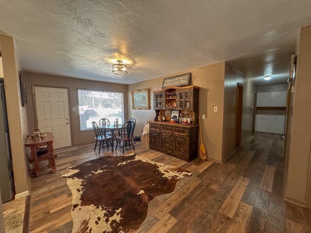 dining space with a textured ceiling, baseboards, and wood finished floors