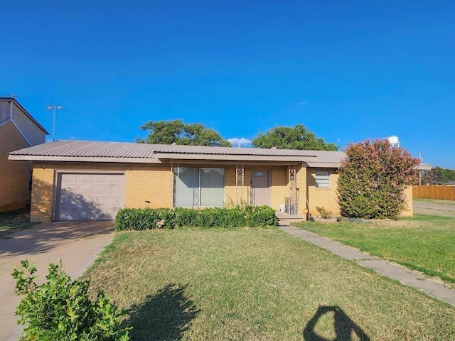 single story home with a garage, driveway, metal roof, a front yard, and brick siding