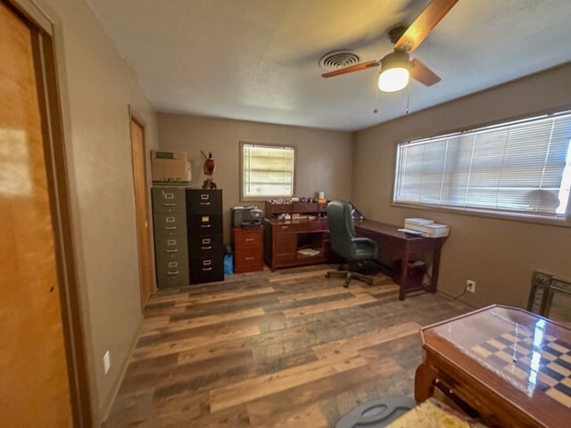 office area featuring a ceiling fan, visible vents, baseboards, and wood finished floors