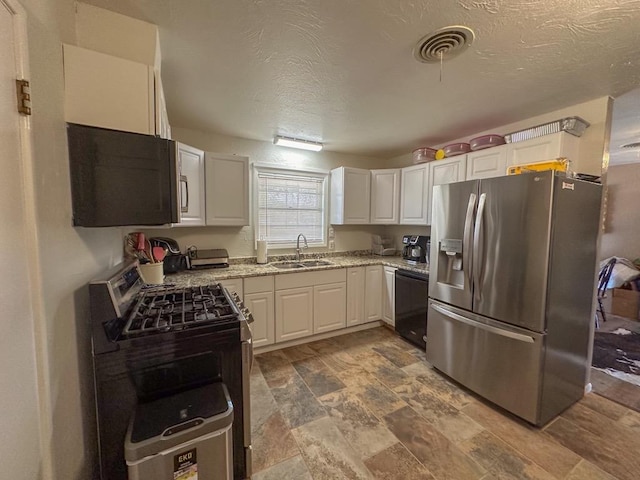 kitchen featuring light stone counters, stainless steel appliances, a sink, visible vents, and white cabinetry