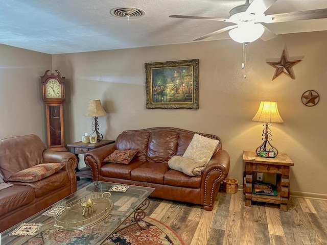 living area featuring a ceiling fan, baseboards, visible vents, and wood finished floors