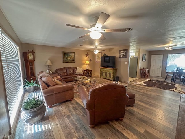 living room with a textured ceiling, wood finished floors, and a ceiling fan