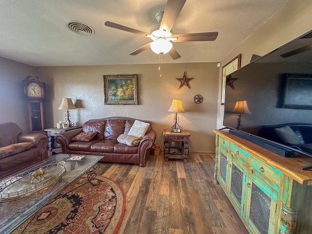 living area with a ceiling fan, visible vents, and wood finished floors