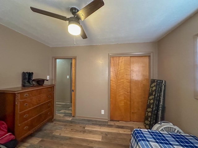 bedroom featuring ceiling fan, a closet, wood finished floors, and baseboards