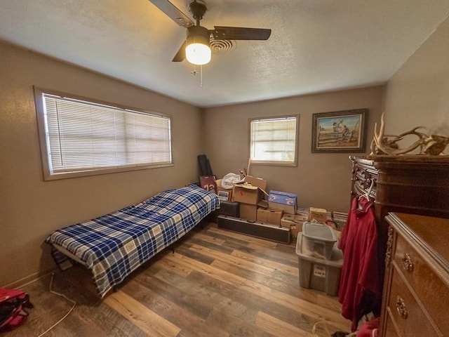 bedroom featuring ceiling fan, a textured ceiling, and wood finished floors