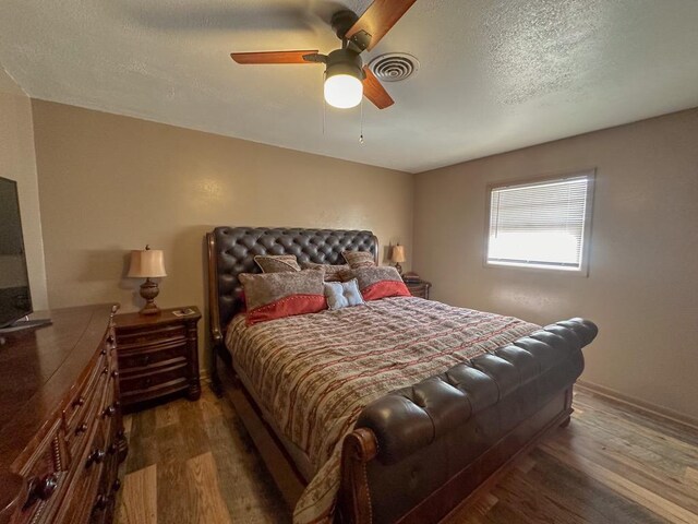 bedroom featuring visible vents, dark wood-type flooring, a ceiling fan, a textured ceiling, and baseboards