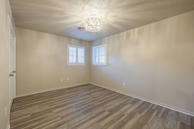 unfurnished room featuring dark hardwood / wood-style floors, an inviting chandelier, and a textured ceiling