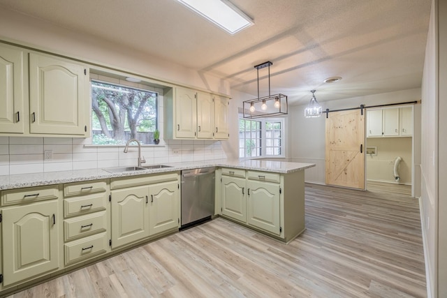 kitchen with sink, dishwasher, plenty of natural light, a barn door, and kitchen peninsula