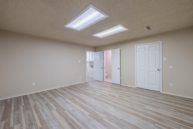 spare room with a textured ceiling and light wood-type flooring