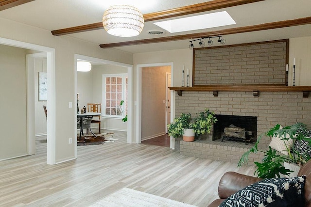 living room with a skylight, a fireplace, and light hardwood / wood-style flooring