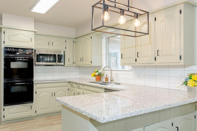 kitchen featuring sink, black double oven, light stone counters, decorative backsplash, and kitchen peninsula