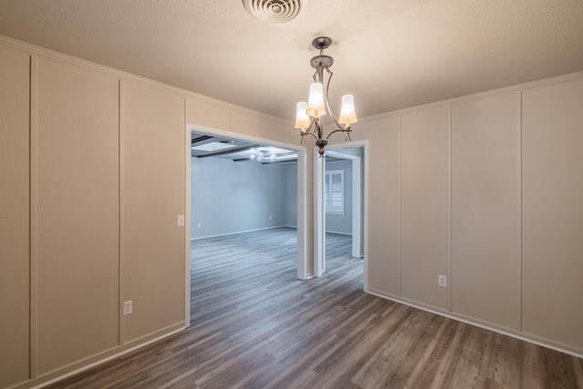 unfurnished dining area featuring a textured ceiling, dark wood-type flooring, and a chandelier