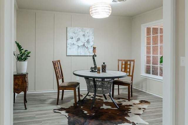 dining space with crown molding and wood-type flooring