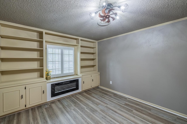 unfurnished living room with crown molding, light hardwood / wood-style flooring, built in features, and a textured ceiling