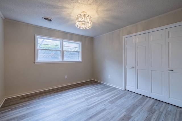 unfurnished bedroom featuring ornamental molding, a textured ceiling, and light hardwood / wood-style floors