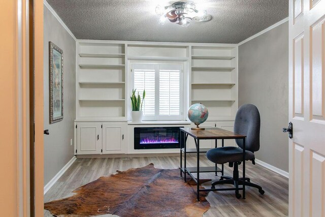 office area featuring crown molding, built in shelves, light hardwood / wood-style floors, and a textured ceiling