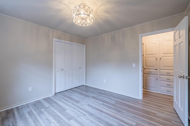 unfurnished bedroom with ornamental molding, a notable chandelier, a textured ceiling, and light hardwood / wood-style flooring