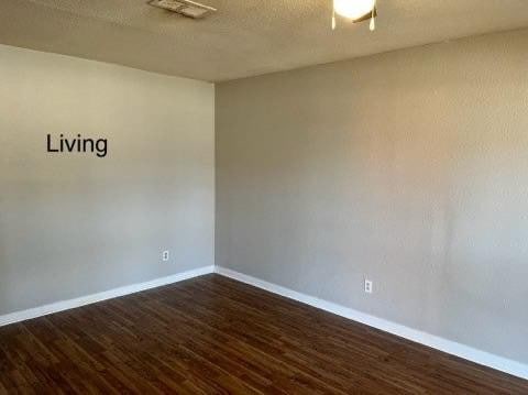 empty room featuring dark wood-type flooring and a textured ceiling