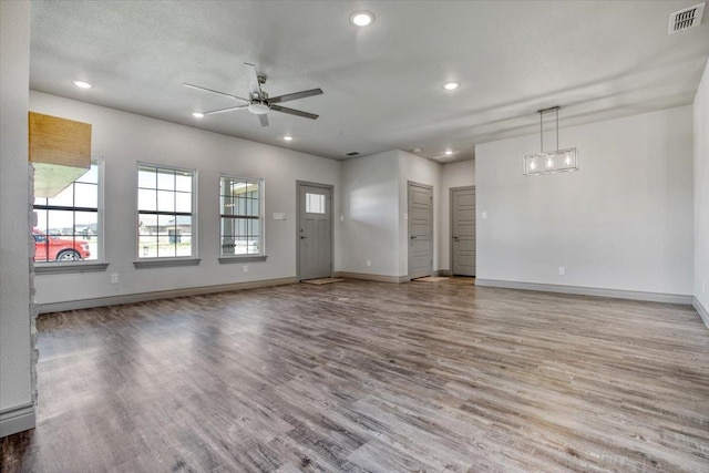 unfurnished living room with plenty of natural light, light hardwood / wood-style floors, and ceiling fan