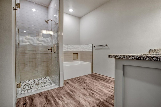 bathroom with vanity, independent shower and bath, and hardwood / wood-style floors