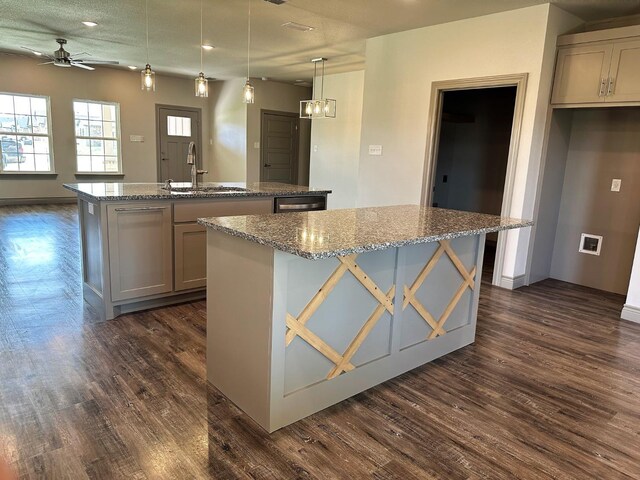 kitchen featuring sink, light stone counters, hanging light fixtures, a center island with sink, and dark hardwood / wood-style floors